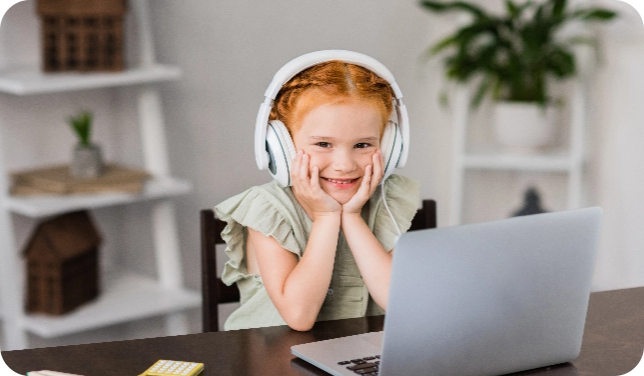 Een kind dat blij lacht en luistert via een koptelefoon achter een laptop.