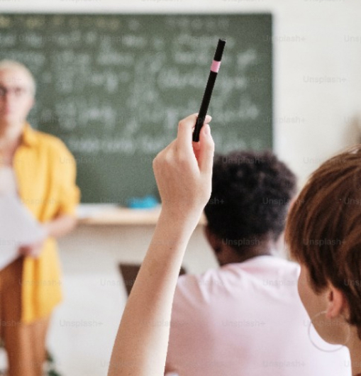 jongen steekt hand op met pen in de klas